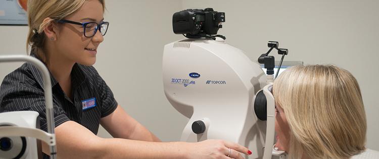 Image shows an optometrist performing an OCT scan on a patient. 