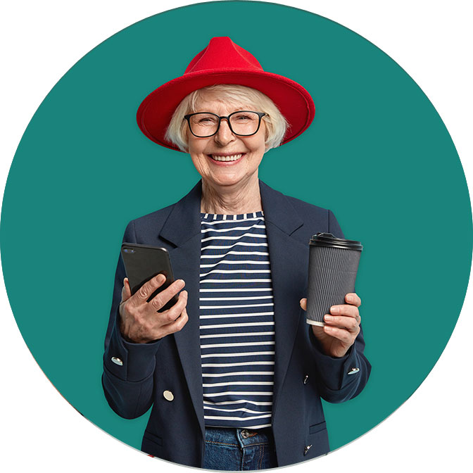 Image of happy older woman in red hat. She is holding a phone and cup of drink. 